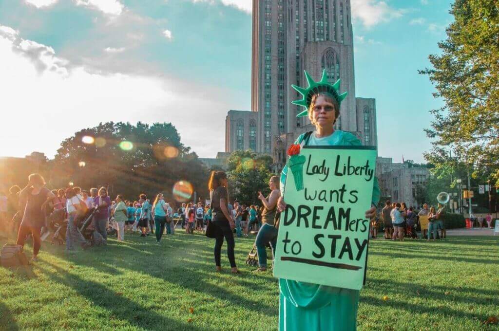 Protestas para defender el programa DACA, una mujer sostiene un cartel disfrazada de la estatua de la libertad.