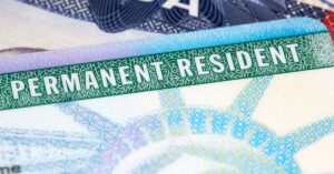 close-up of a U.S. Permanent Resident card with a visible green 'PERMANENT RESIDENT' label and the Statue of Liberty design