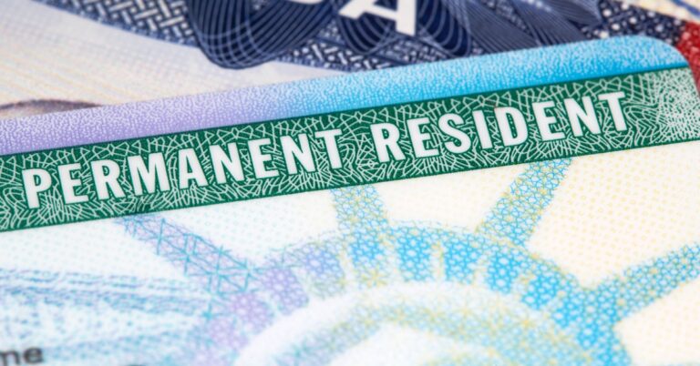 close-up of a U.S. Permanent Resident card with a visible green 'PERMANENT RESIDENT' label and the Statue of Liberty design