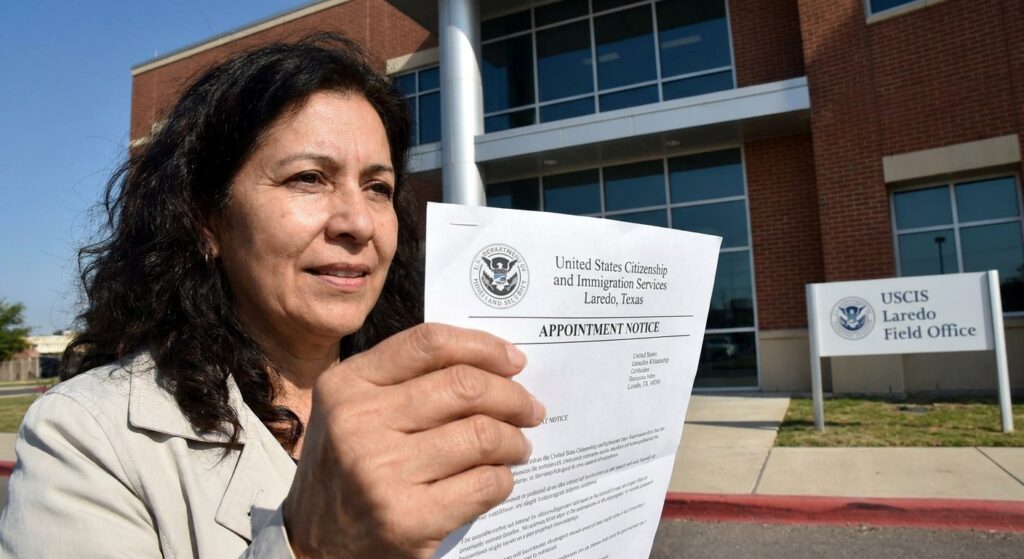 USCIS en Laredo TX: trámites, citas y cómo prepararte 2 Exterior de la oficina de USCIS Laredo TX en Maher Avenue, con una persona esperando afuera sosteniendo una notificacion de cita.