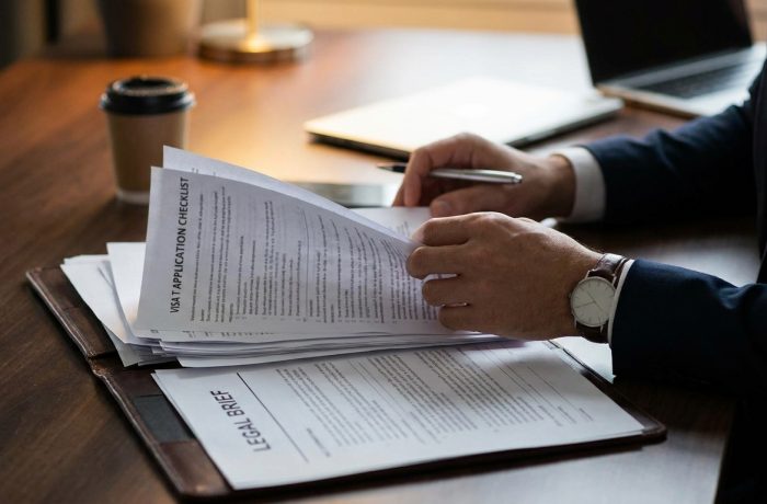 Manos sobre escritorio revisando documentos y lista de control para los visa t requisitos de proteccion.