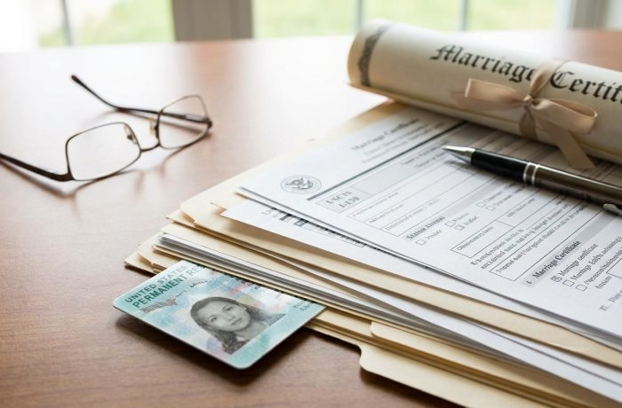 Tarjeta de Residencia (Green Card) con pila de documentos migratorios y certificado de matrimonio, simbolizando el proceso de casarse con ciudadano americano.